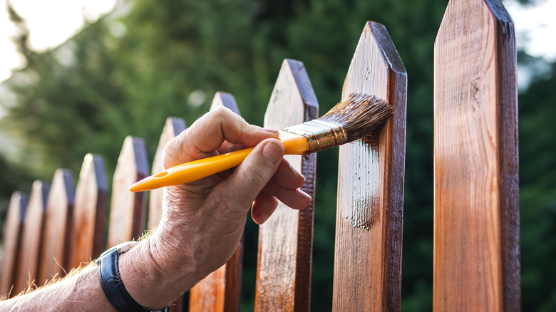 Person staining fence pickets on a privacy fence
