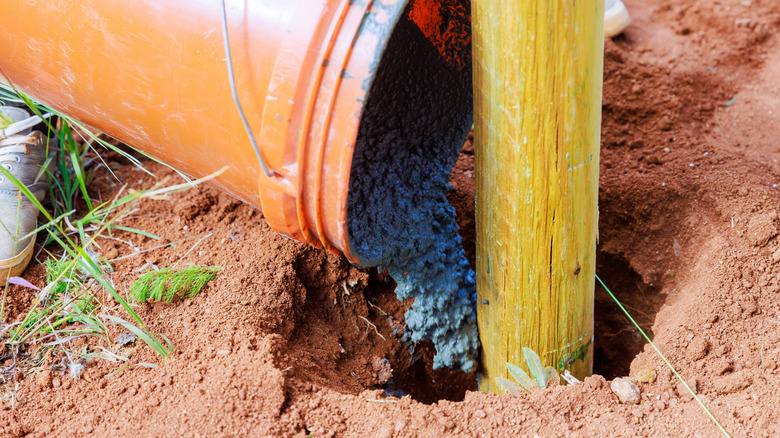 Adding concrete to a wood fence post hole