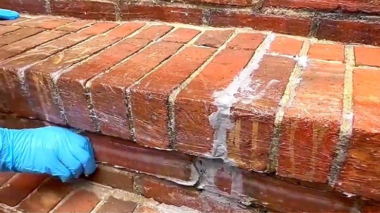 A DIYer prepares brick stairs for covering with gravel
