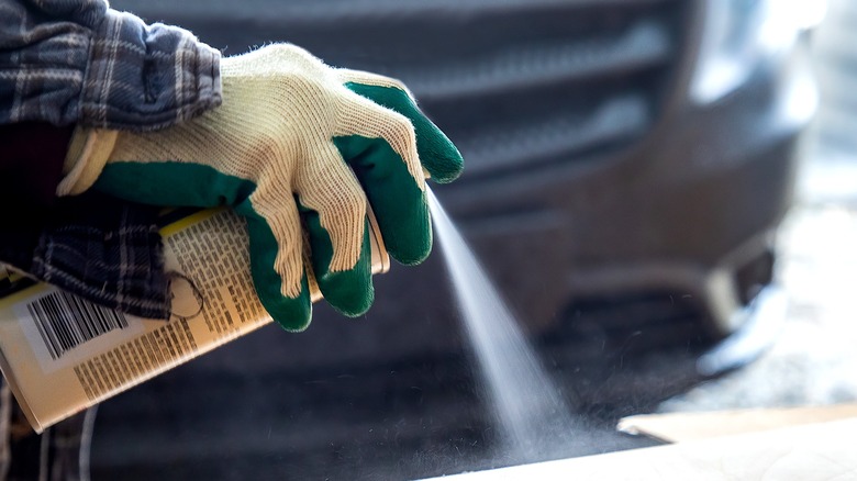 Close-up of a person's gloved hand using a spray paint can