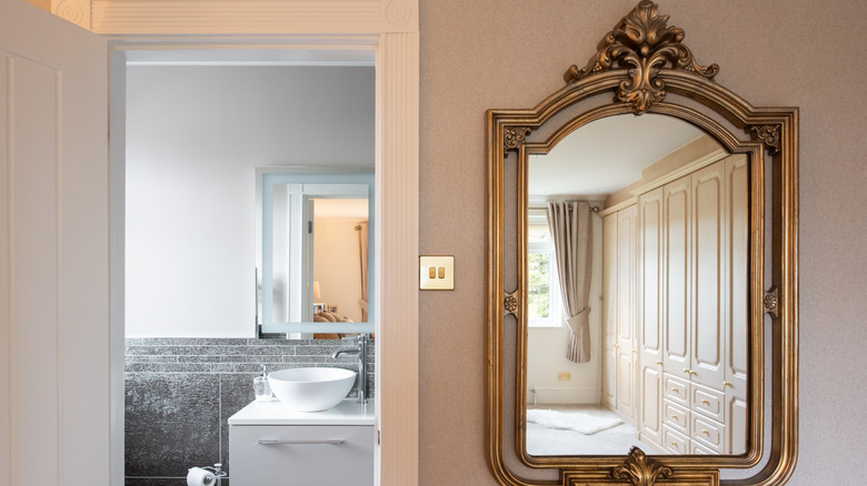 A large gilded mirror in a bedroom