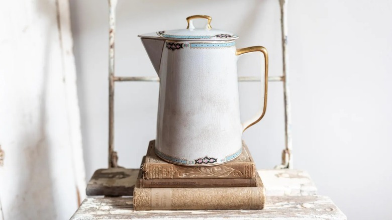 An antique ironstone pitcher with crazing on a stack of old books
