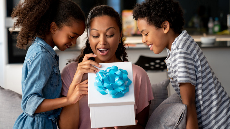 Children watching mother open gift