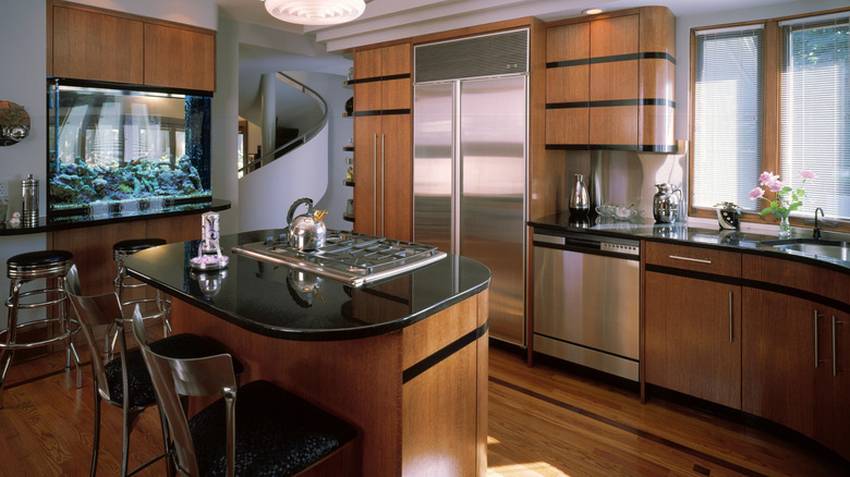 Contemporary Art Deco kitchen with brown and black cabinets, black countertops, and island with gas stove