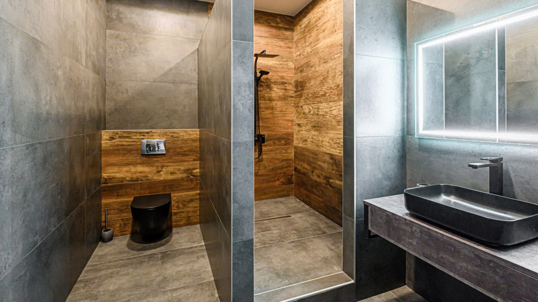 A modern bathroom with black fixtures, tile, and wood.