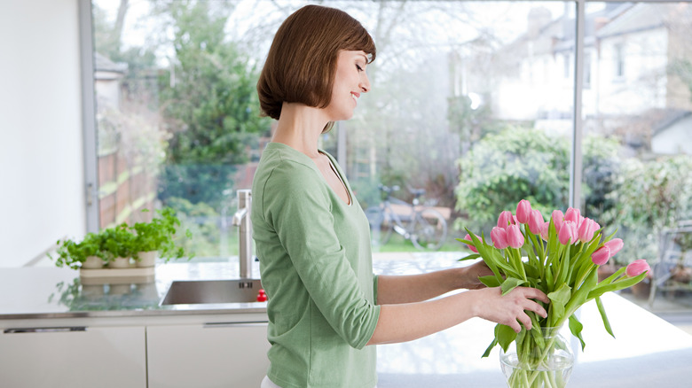 woman putting tulips in vase