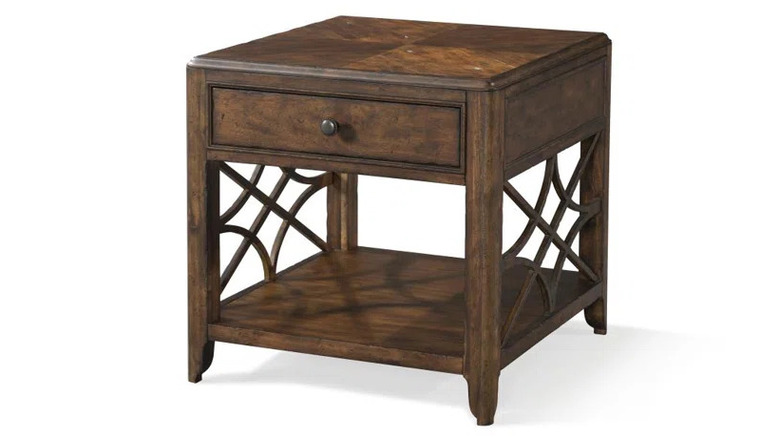 A brown wooden side table with a drawer and side detailing