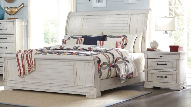 White nightstand with two drawers next to a large white bed