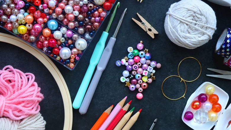 A variety of different craft supplies are scattered on a black surface.