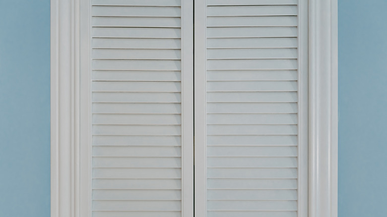 A pair of white, bi-fold closet doors stand closed amid the light blue hue of an adjoining wall in this home deco photo.