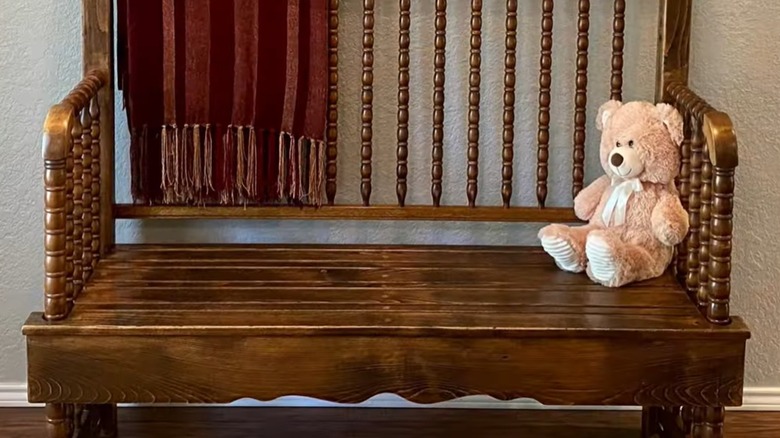 An attractive wooden bench holds a blanket and teddy bear.