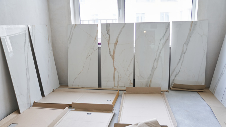 Large marble slabs leaned against a wall in a room ready for installation and empty boxes on the floor