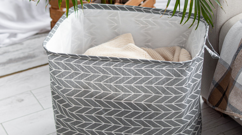 Fabric storage bin next to sofa and potted palm