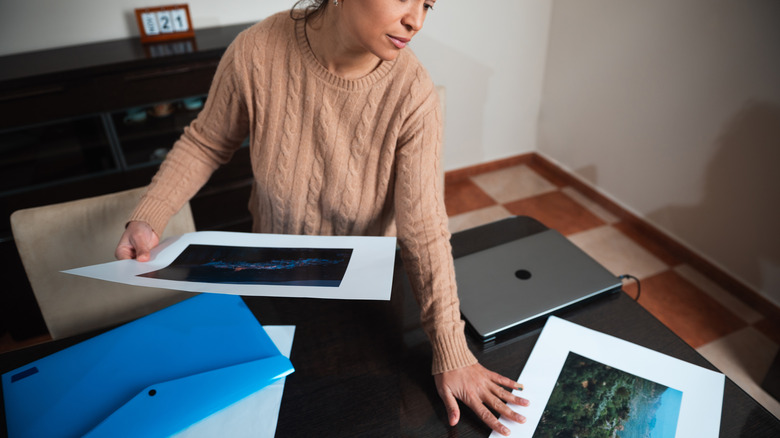 a woman holding and inspecting printed landscape photos
