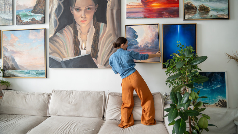 Woman hanging wall art in a home