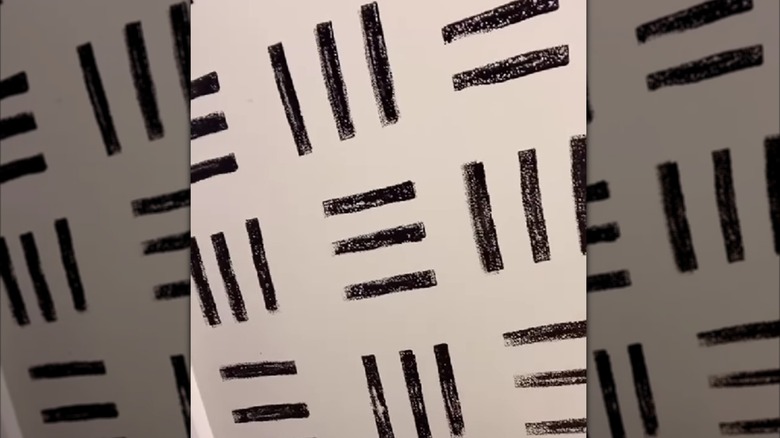 A person uses a sponge to stamp black lines on a white wall