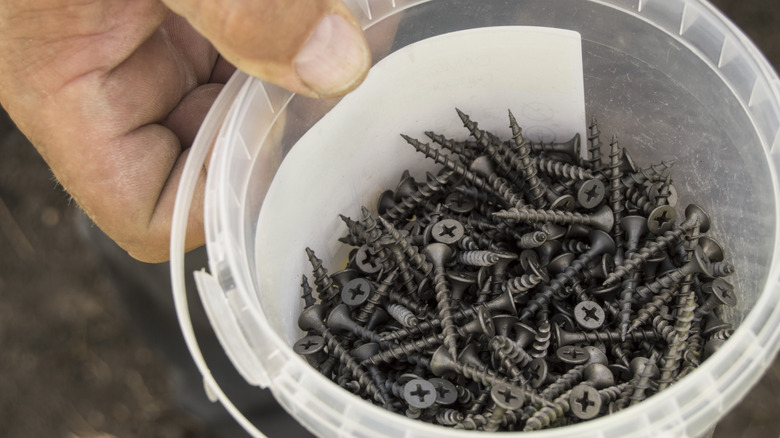 man holding a bucket of small screws