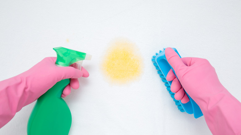 Gloved hands clean yellow stain