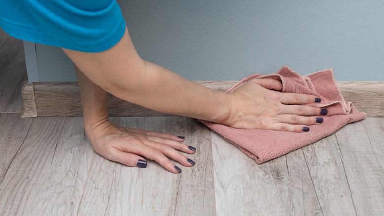 person cleaning baseboards by hand