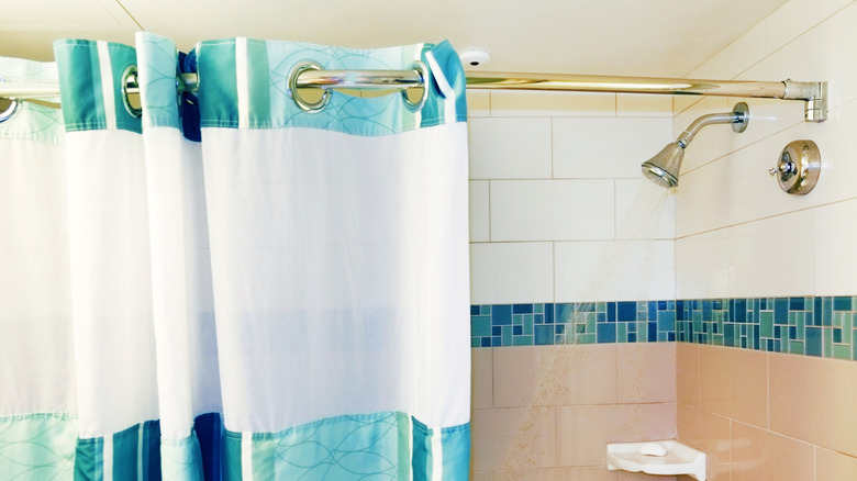 A blue and white shower curtain for an outdated shower