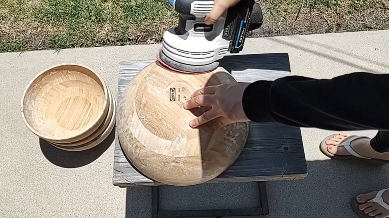 woman sanding an IKEA BLANDA MATT bamboo bowl for DIY table