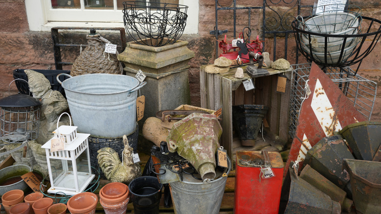 Vintage garden items with sales tags piled up outside a house.