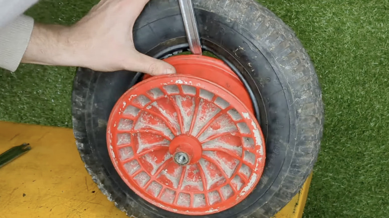 A person removes a wheelbarrow tire from the rim.