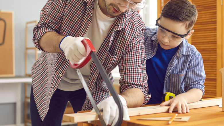 father and son sawing a board