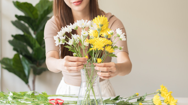 Woman arranging flowers in an undecorated glass jar