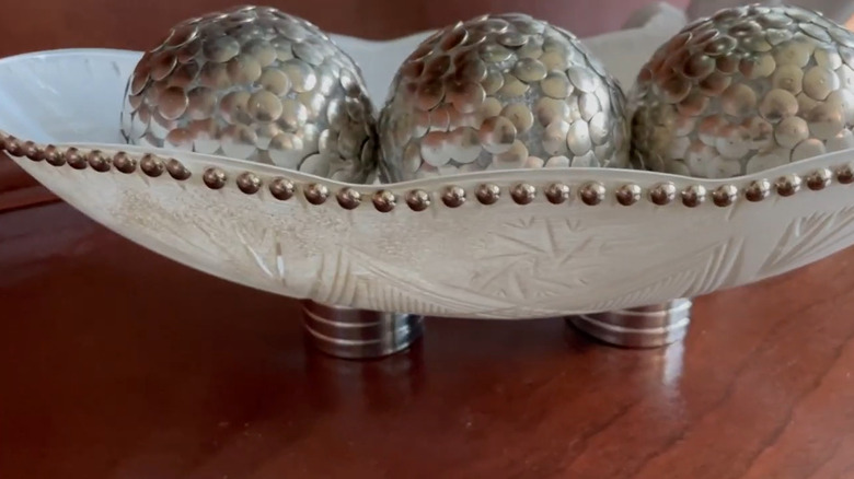 A Dollar Tree DIY décor bowl with silver balls inside.