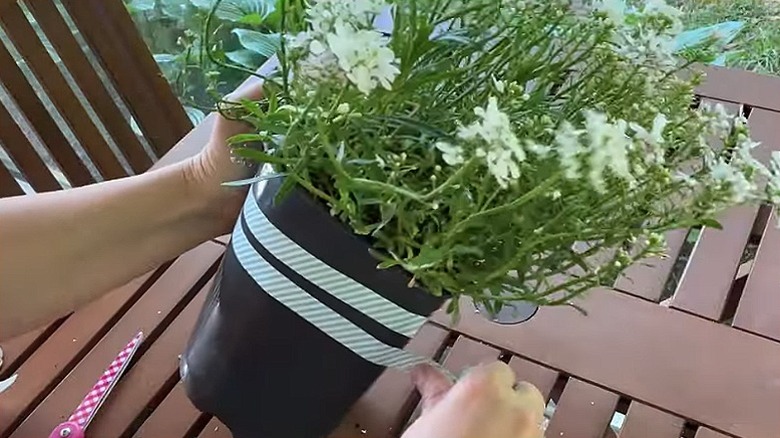 A crafter adding washi tape to a plain nursery pot