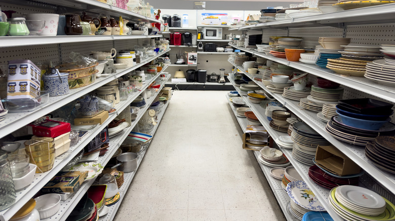 an aisle in a thrift store is lined with kitchenware items, with small appliances in the background