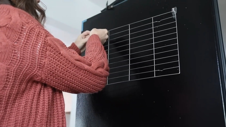 Woman hanging a cooling rack on a wall