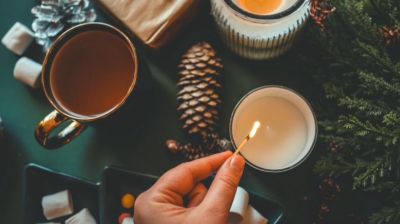Person lighting holiday candle on table
