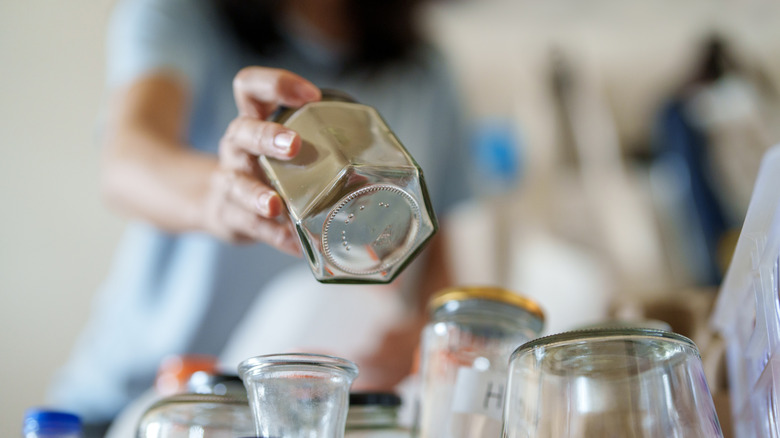 Person picking out a jar from a collection of glass jars