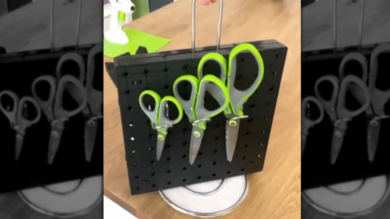 A DIY paper towel and pegboard organizer holding pairs of scissors