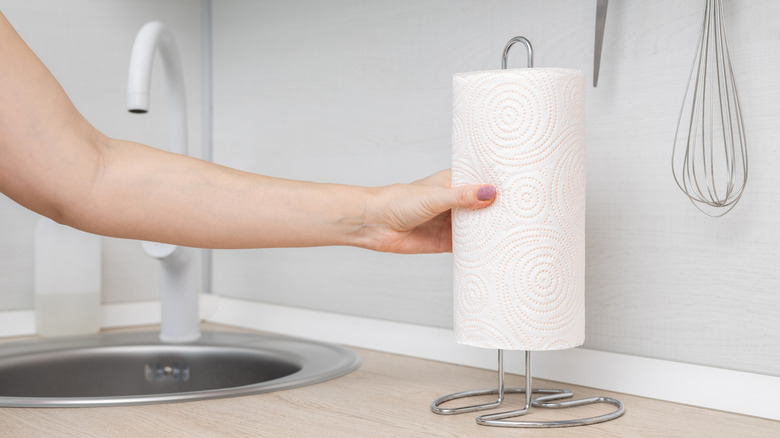 person putting paper towel on paper towel holder