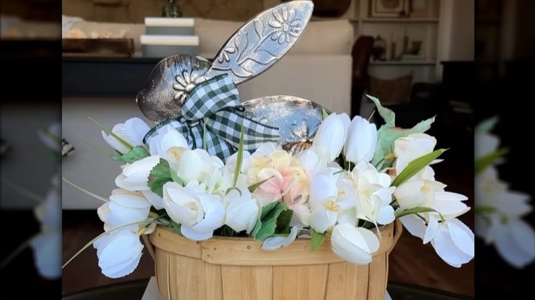 A stunning spring centerpiece made using a metal bunny, a basket, and some artificial flowers.
