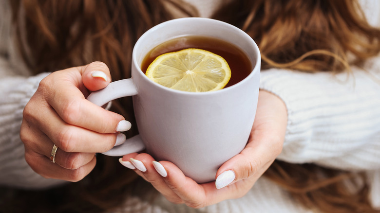 woman holding cup of tea with lemon