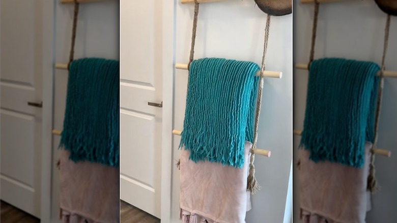 A DIY blanket ladder storing a pink and a blue blanket, created by items from the Dollar Store.