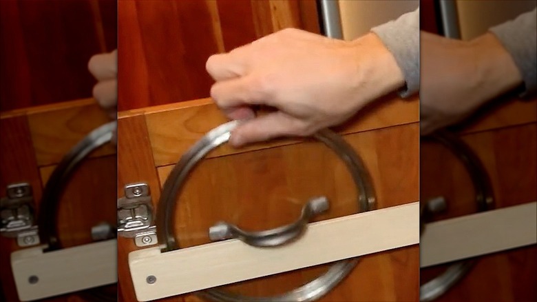 Putting a pot lid in its storage rack