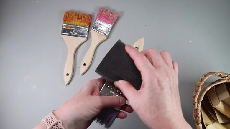 Female hands sanding down a wooden paintbrush handle