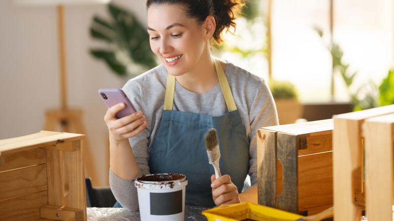 Woman painting a wooden crate