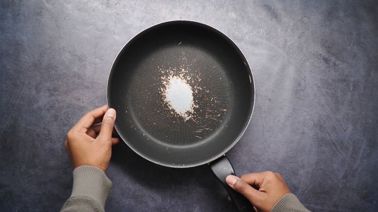 Hands holding a worn-out frying pan