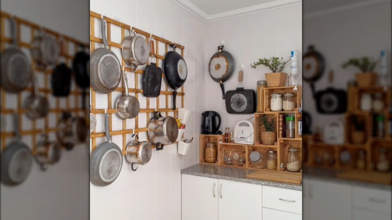 Pots and pans hanging on a mounted garden trellis in a kitchen.