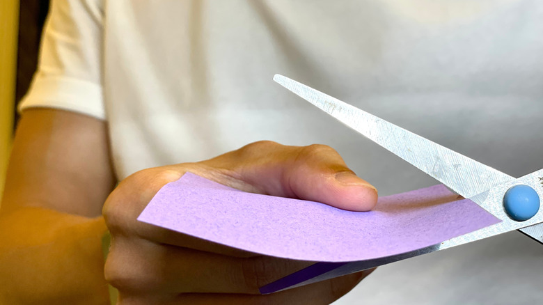 person cutting colorful piece of paper or plastic