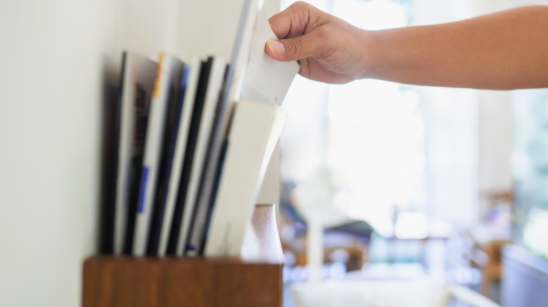 Close-up of a person grabbing a magazine from a magazine rack