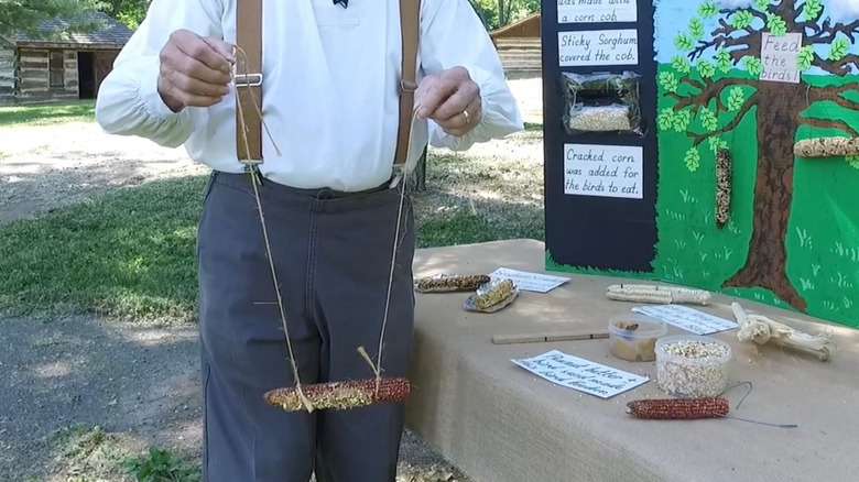 Man holding up corn cob feeder