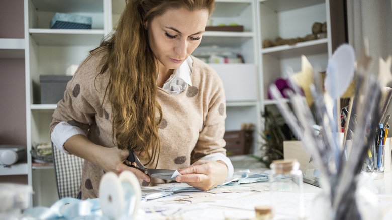 A woman using scissors to cut paper on a table