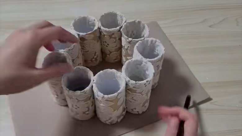Person making a DIY storage container using toilet paper rolls